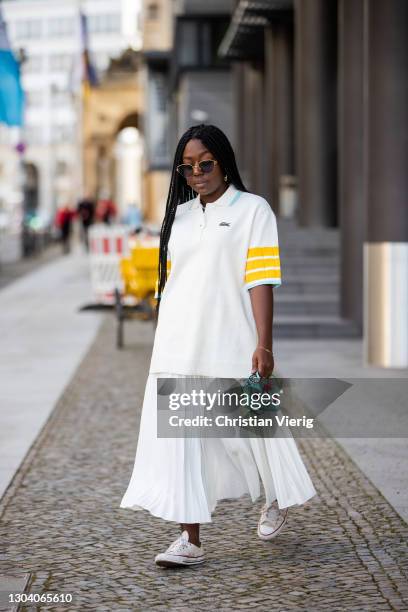 Lois Opoku is seen wearing white polo and skirt Lacoste, Fendi bag, Converse sneaker, Boucheron sunglasses on February 25, 2021 in Berlin, Germany.