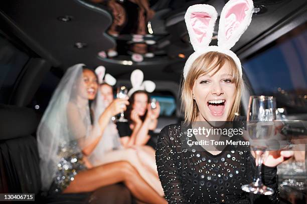 woman in bunny ears drinking champagne in limo - limo stockfoto's en -beelden