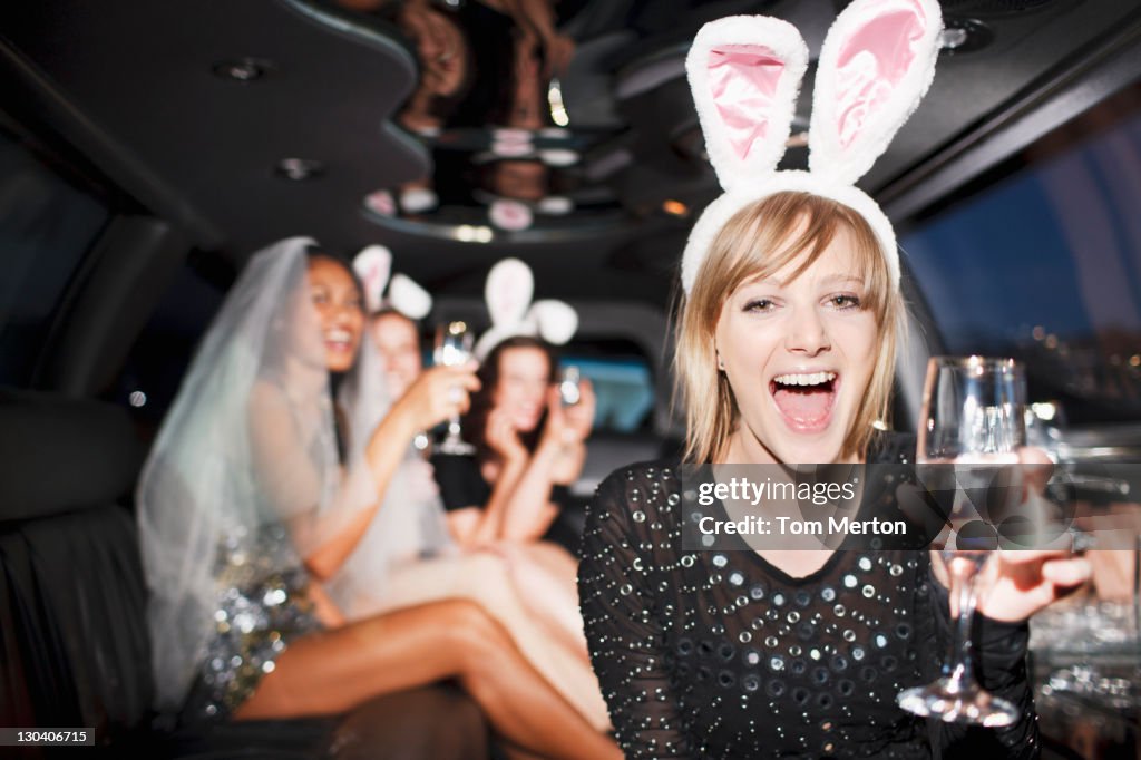 Woman in bunny ears drinking champagne in limo