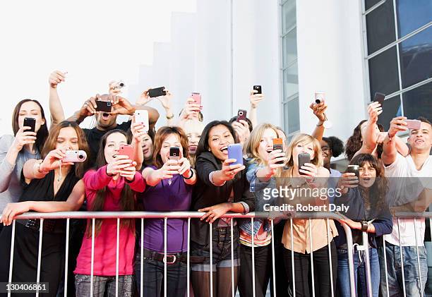fans taking pictures with cell phones behind barrier - paparazzi stockfoto's en -beelden