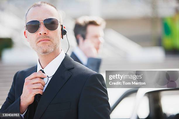 bodyguard talking into earpiece - bodyguard stock pictures, royalty-free photos & images