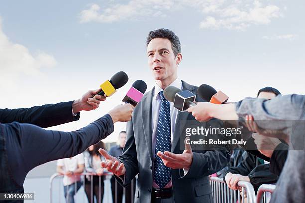 politician talking into reporters' microphones - journalist stock pictures, royalty-free photos & images