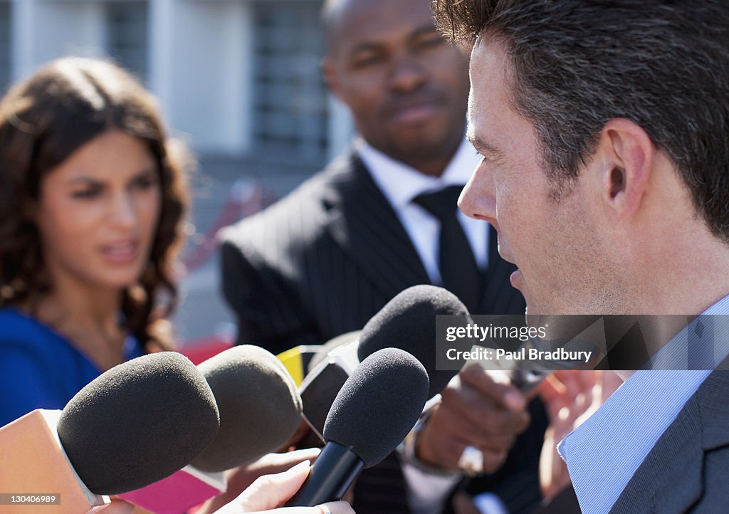 Politician talking into reporters' microphones