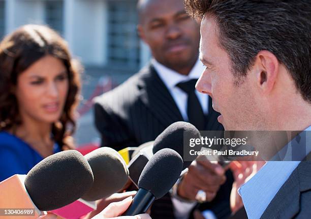 politician talking into reporters' microphones - england press conference stock pictures, royalty-free photos & images