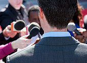 Politician talking into reporters' microphones