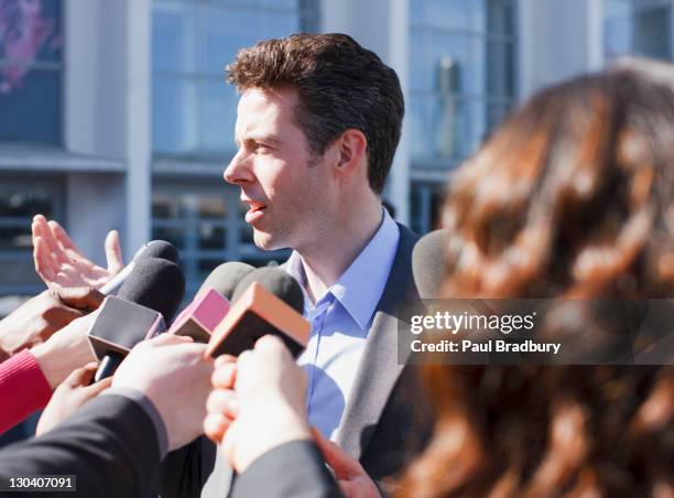 politician talking into reporters' microphones - england press conference stock pictures, royalty-free photos & images