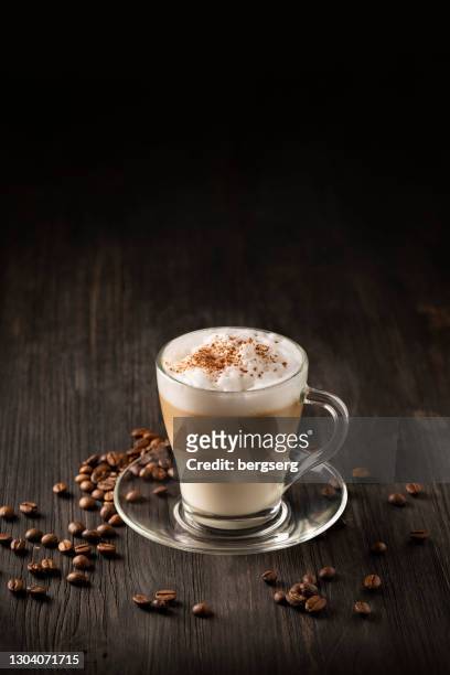 latte macchiato coffee layered with milk, roasted coffee beans on black wooden background - café au lait stock pictures, royalty-free photos & images