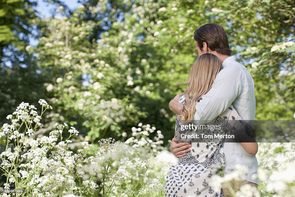 Couple hugging in field of flowers