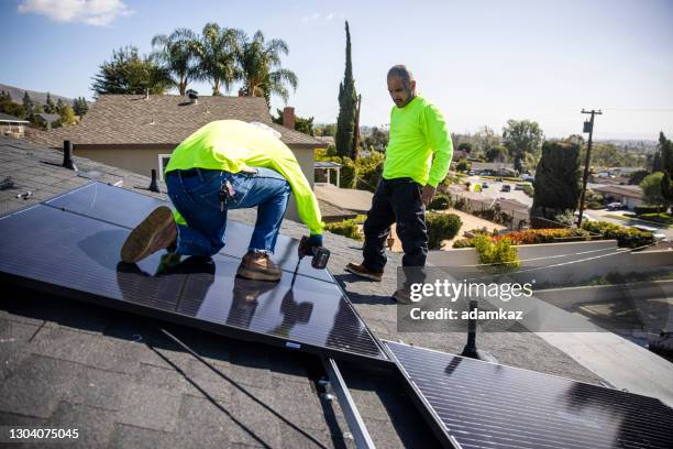 team of workers installing solar panels on residential rooftop in california - panel solar stock pictures, royalty-free photos & images