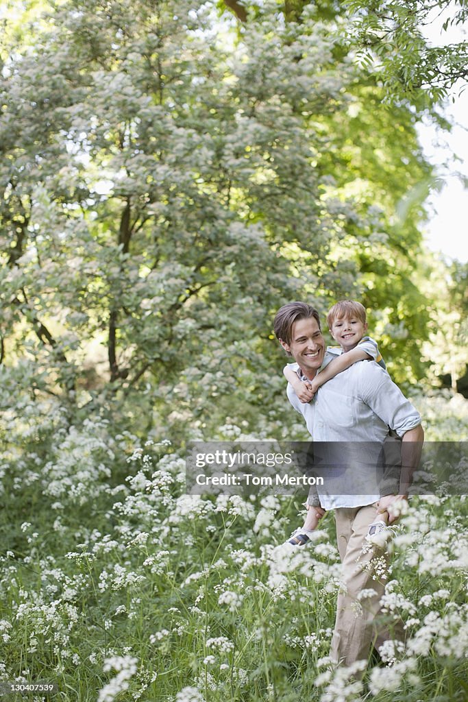 Father carrying son piggyback in park