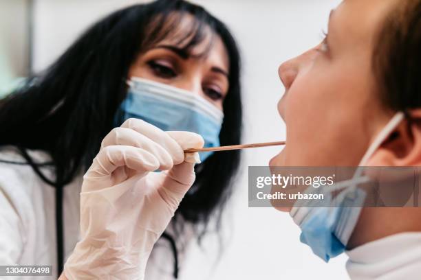 médico femenino tomando prueba de hisopo de garganta de niño - throat photos fotografías e imágenes de stock