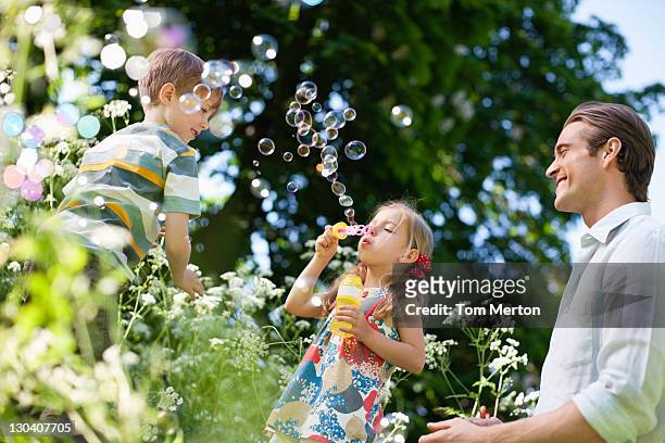 family playing with bubbles outdoors - child blowing bubbles stockfoto's en -beelden