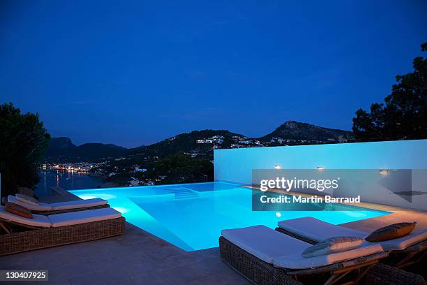 pool with lounge chairs at night - swimming pool night stock pictures, royalty-free photos & images