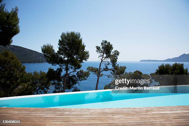 piscine à débordement avec vue sur les arbres et les toits de la ville - vue dans la mer photos et images de collection