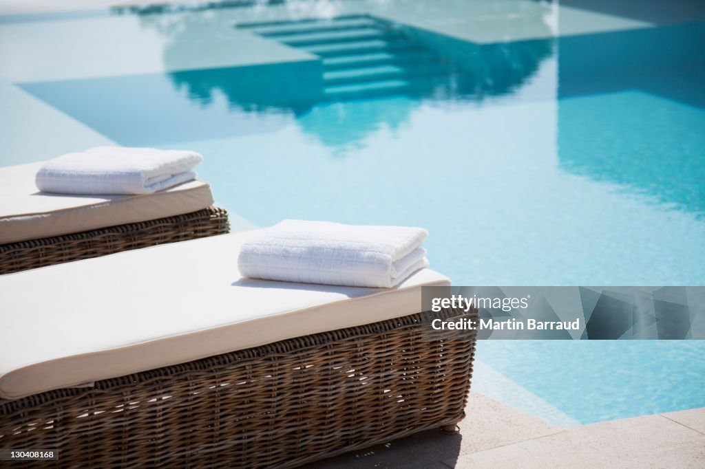 Folded towels on lounge chairs beside pool