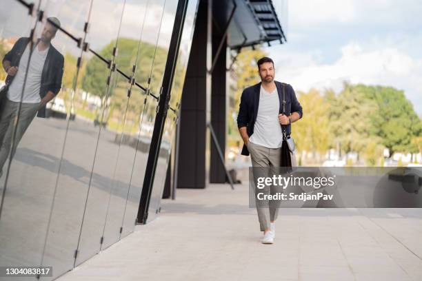 moderner junger geschäftsmann geht zur arbeit - hände in den taschen stock-fotos und bilder