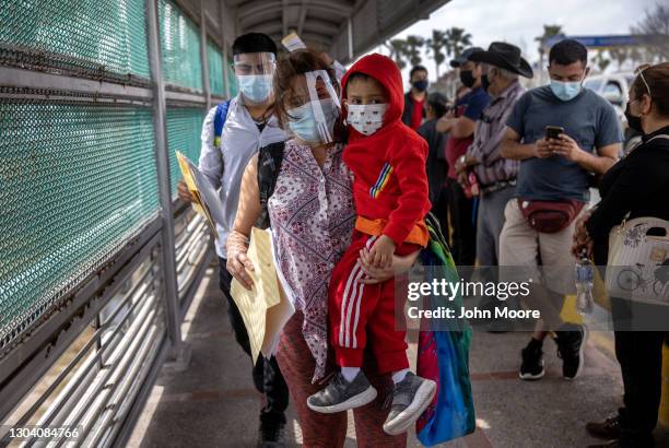 Honduran mother carries her son across the U.S.-Mexico border as part of a group of at least 25 asylum seekers who where were allowed to travel from...