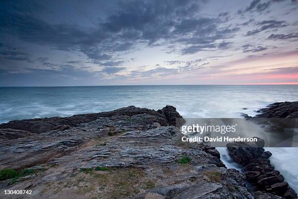 rocks jutting into ocean under sky - キブロン ストックフォトと画像