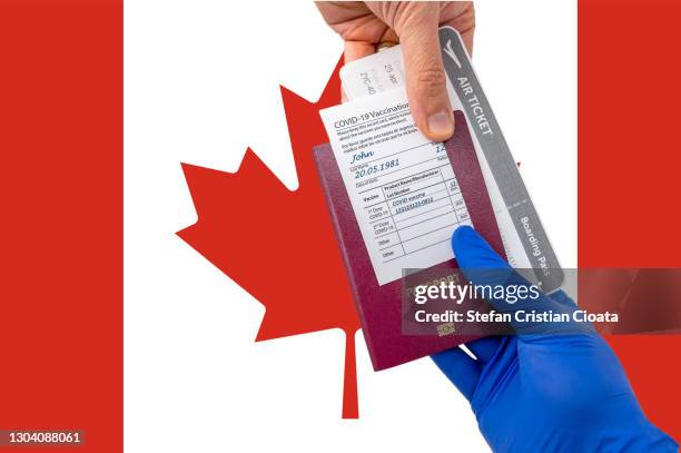 human hand holding a passport and vaccination certificate - canadian passport stock-fotos und bilder