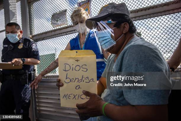 An asylum seeker carrying a sign that reads 'God Bless Mexico' crosses the U.S.-Mexico border as a group of at least 25 immigrants were allowed to...