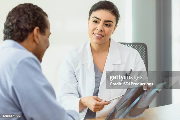 female doctor discusses x-ray with male patient - orthopedic surgery stock pictures, royalty-free photos & images