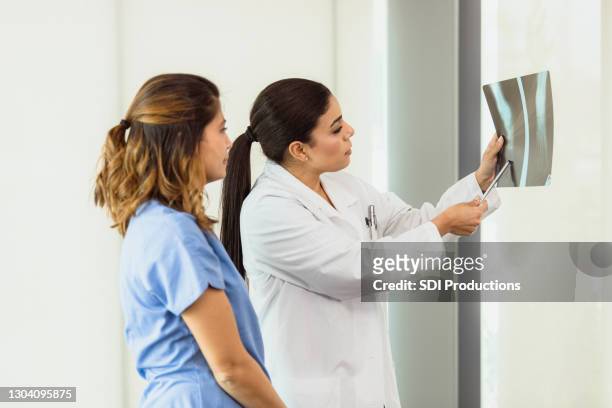 orthopedic doctors review patient's x-ray - orthopedic surgery stock pictures, royalty-free photos & images