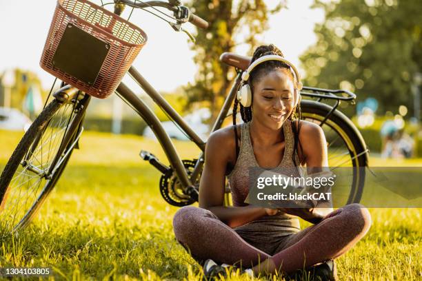 young african american woman is reading a book in nature - read book outside young woman stock pictures, royalty-free photos & images