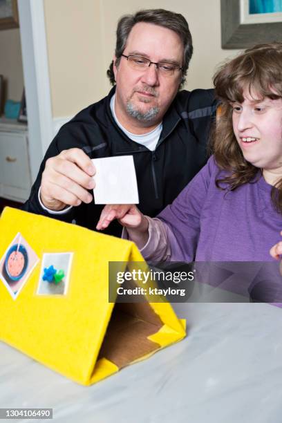 vader van non-verbale jonge vrouw helpt haar met haar schoolwerk van het matchen van foto's met de bijbehorende woorden - choice student stockfoto's en -beelden