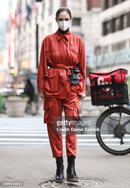 Coco Rocha is seen wearing a red outfit, black boots and Tod's purse outside the Christian Siriano show during New York Fashion Week F/W21 on...