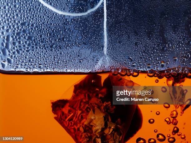 tea bag inside orange liquid close up - dried tea leaves ストックフォトと画像