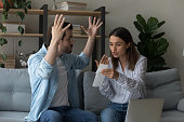 Stressed emotional couple arguing fighting when checking financial papers