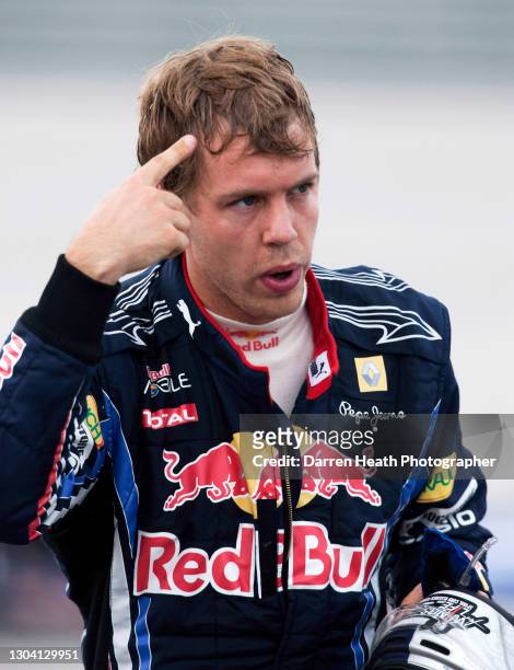 German Red Bull Racing Formula One driver Sebastian Vettel points a finger to his head to signal his opinion of his Red Bull Racing teammate...