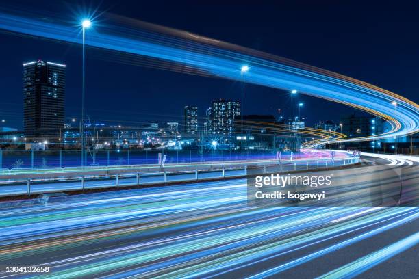 urban skyline and light trails against clear sky at night - street light stock pictures, royalty-free photos & images