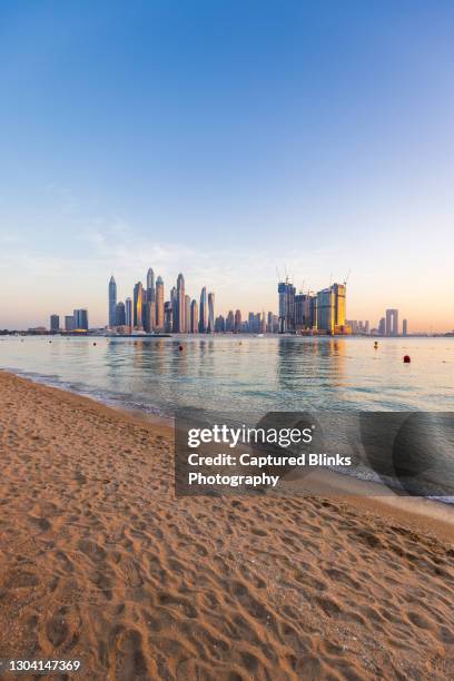 beachside view of dubai marina skyline across man made lake - dubai strand stock-fotos und bilder