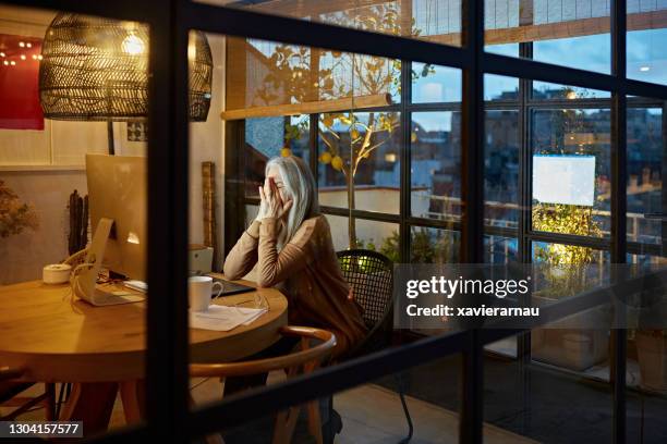 retired woman in home office experiencing emotional stress - unusual imagens e fotografias de stock