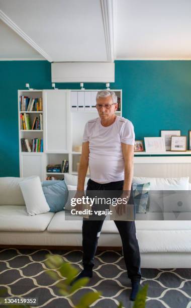 hombre mayor haciendo ejercicio en casa con libros - ejercicio-cardiovascular fotografías e imágenes de stock