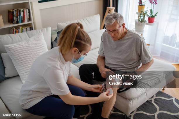 physiotherapist is applying electro stimulation in physical therapy to a senior man knee - electrode stock pictures, royalty-free photos & images