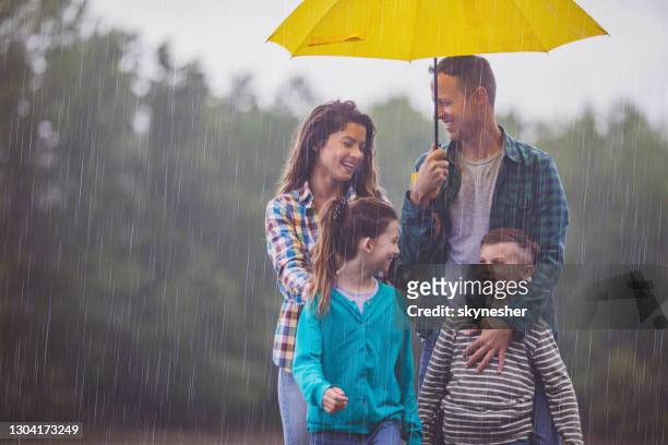 happy family talking while walking on rain in nature. - mother protecting from rain stock pictures, royalty-free photos & images