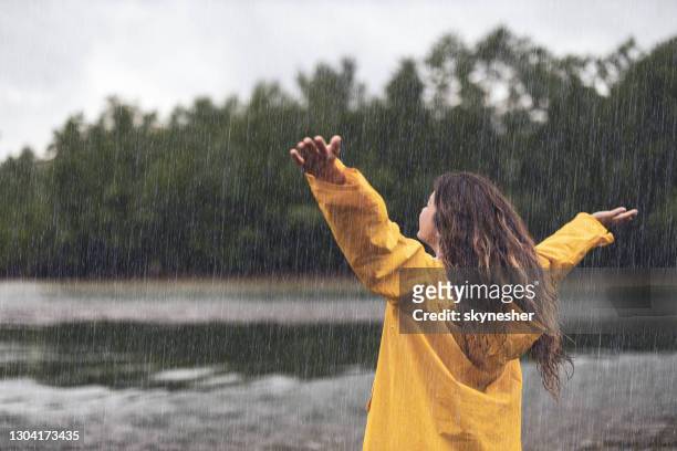 achter mening van een zorgeloze vrouw op regen door de rivier. - rainy day stockfoto's en -beelden