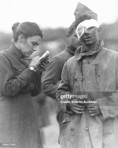 Female Salvation Army worker writies a letter home for a wounded soldier, 1918. US War Department photo.