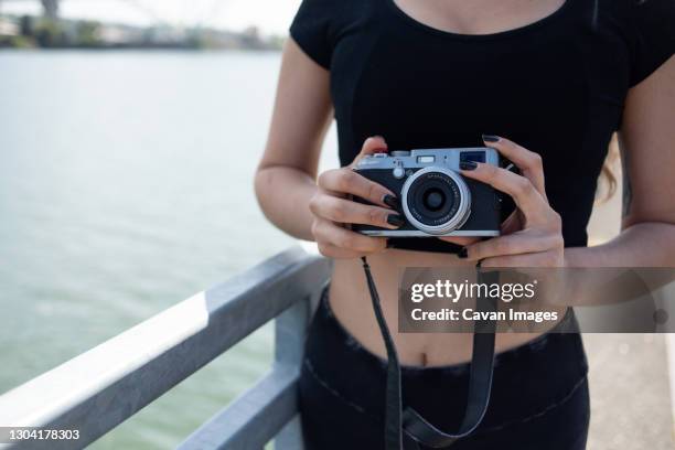 close up of woman holding camera next to river - digital camera stock pictures, royalty-free photos & images