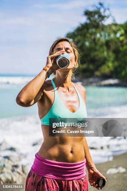 female yogi drinking water on beach - weight loss journey stock pictures, royalty-free photos & images