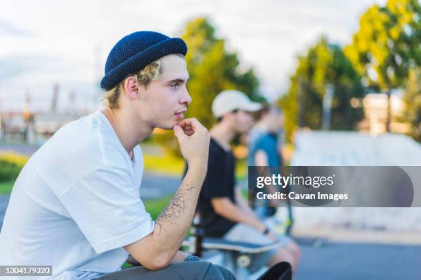young skater in skatepark using his smartphone - skatepark stock-fotos und bilder