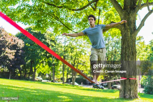 athletic man attempting to slackline - slackline stockfoto's en -beelden