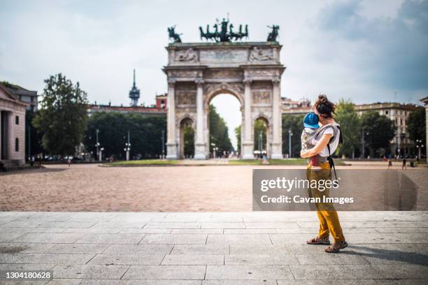 mother carrying her baby visiting milan - marktplatz italien stock-fotos und bilder