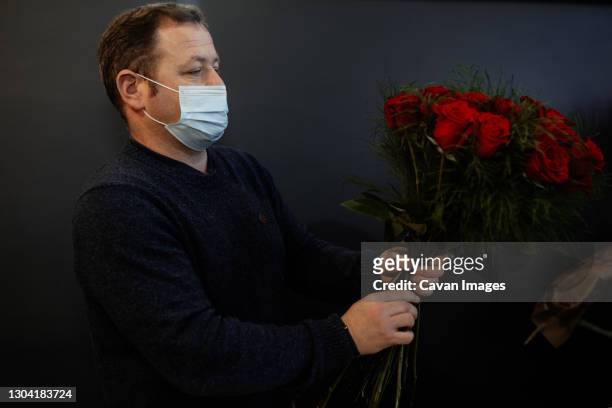 florist making and selling bouquets of red roses for valentines day - dozen roses stockfoto's en -beelden