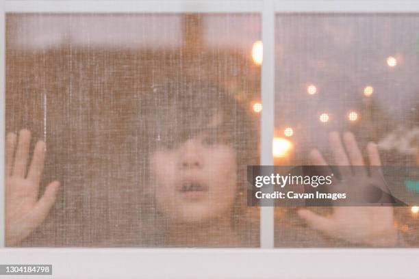 a young boy presses his face and hands up to a screened window - columbus ohio house stock pictures, royalty-free photos & images
