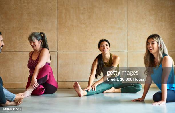 cheerful women in yoga studio smiling and stretching - yoga class stock pictures, royalty-free photos & images