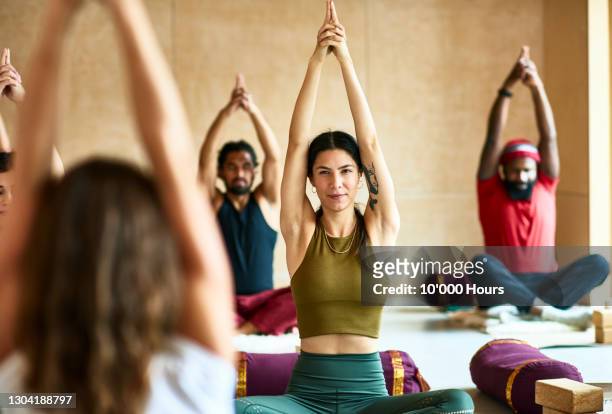 group of people with arms raised in yoga position - yoga stock-fotos und bilder