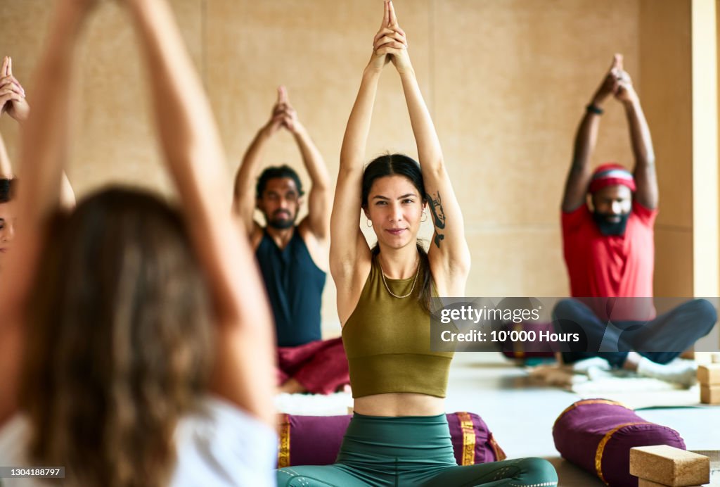 Group of people with arms raised in yoga position